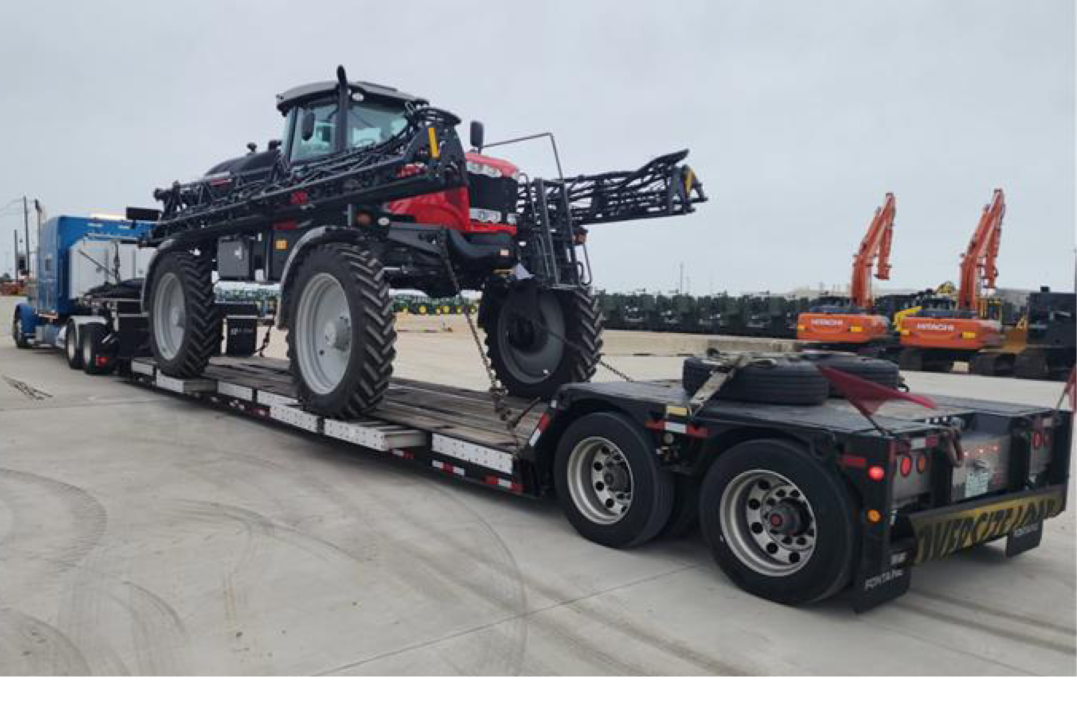 Buchanan hauling agricultural equipment with a double-drop flatbed trailer