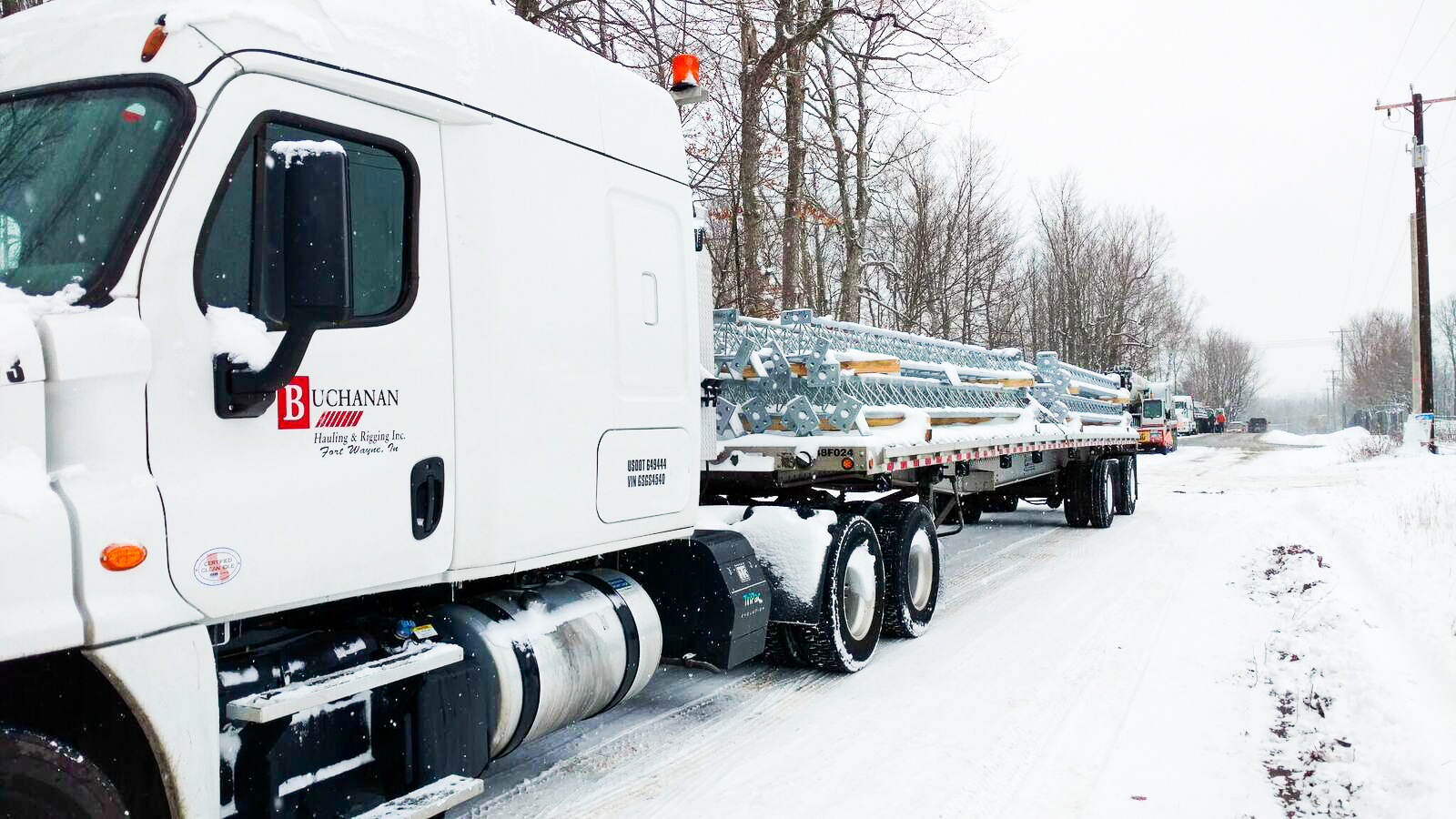 Buchanan Hauling and Rigging semi tractor truck pulling a flatbed of freight in the snow.