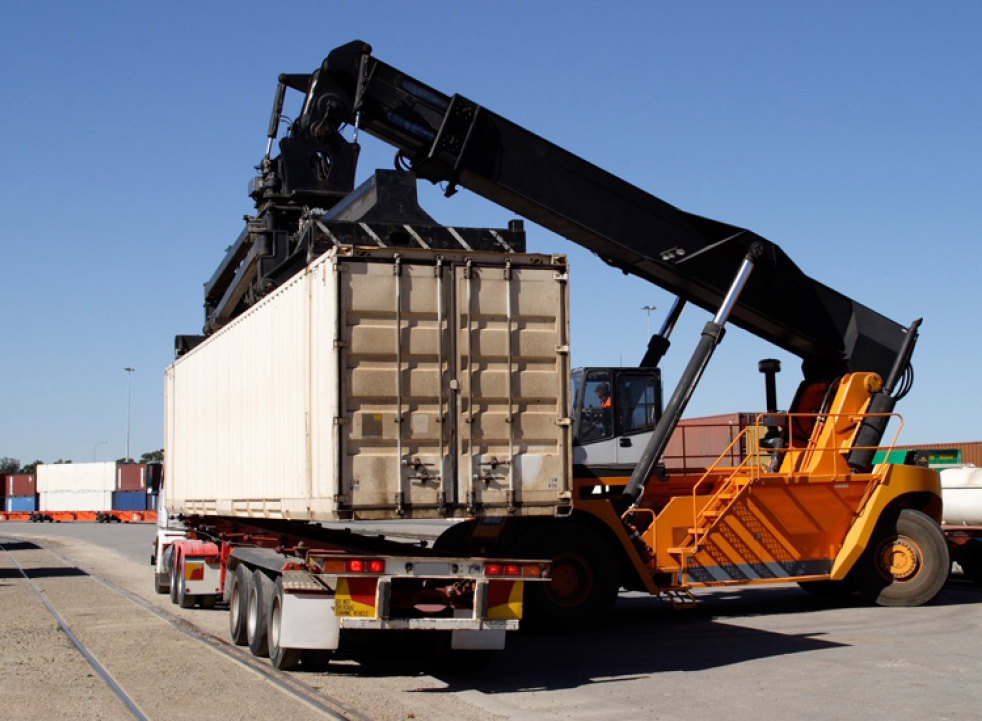 Dock container loader prepares to set a drayage container for transport on a truck carrier.