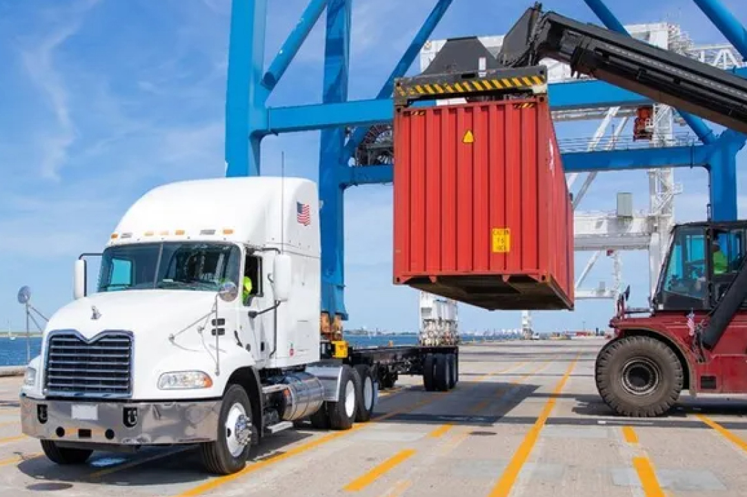Dock container loader prepares to set a drayage container for transport on a truck carrier.