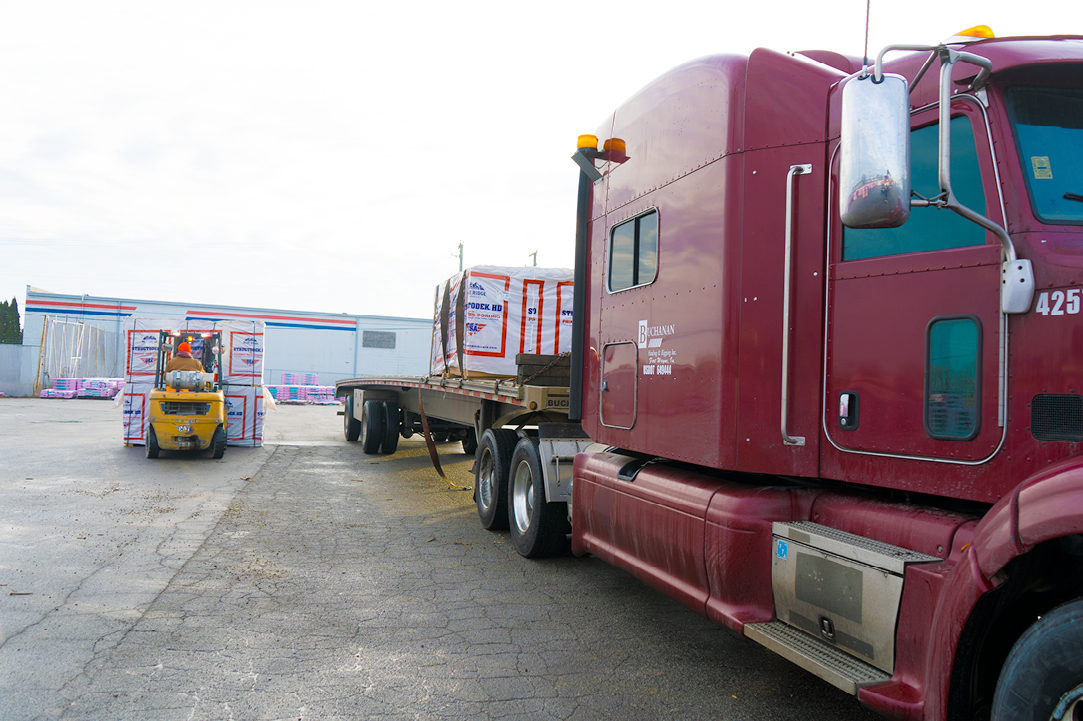 Buchanan Hauling and Rigging truck loading up it's flatbed with retail building materials for a retail store.